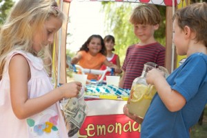 Children (6-12) at lemonade stall, girl (5-7) putting money in bag